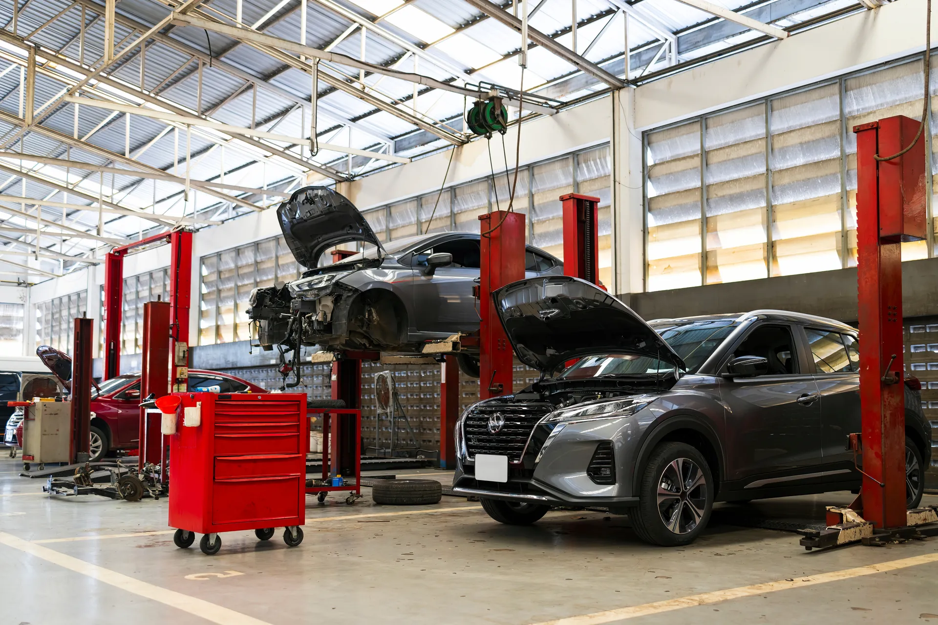 Atelier du garage automobile à Sartrouville : véhicules sur ponts élévateurs, capot ouvert